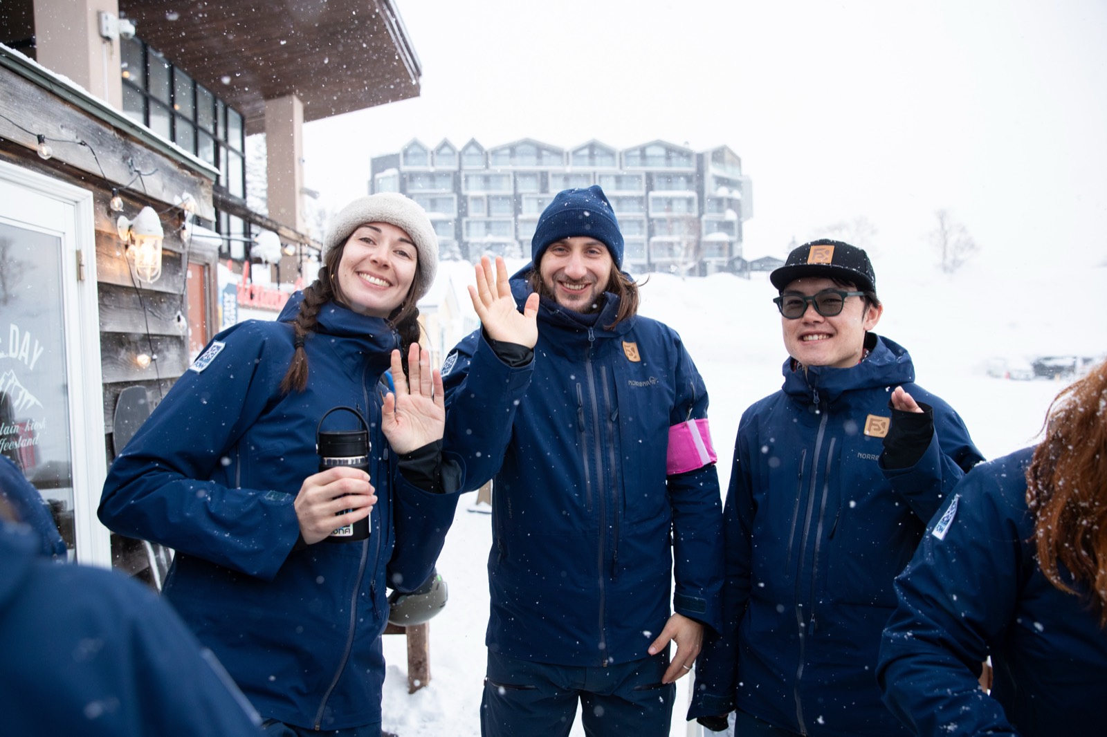 Far East Snowsports instructors smiling and waving at the village base in Niseko