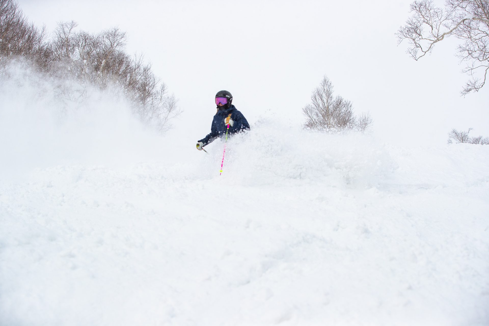 Far East Snowsports skier charging through deep powder in Niseko